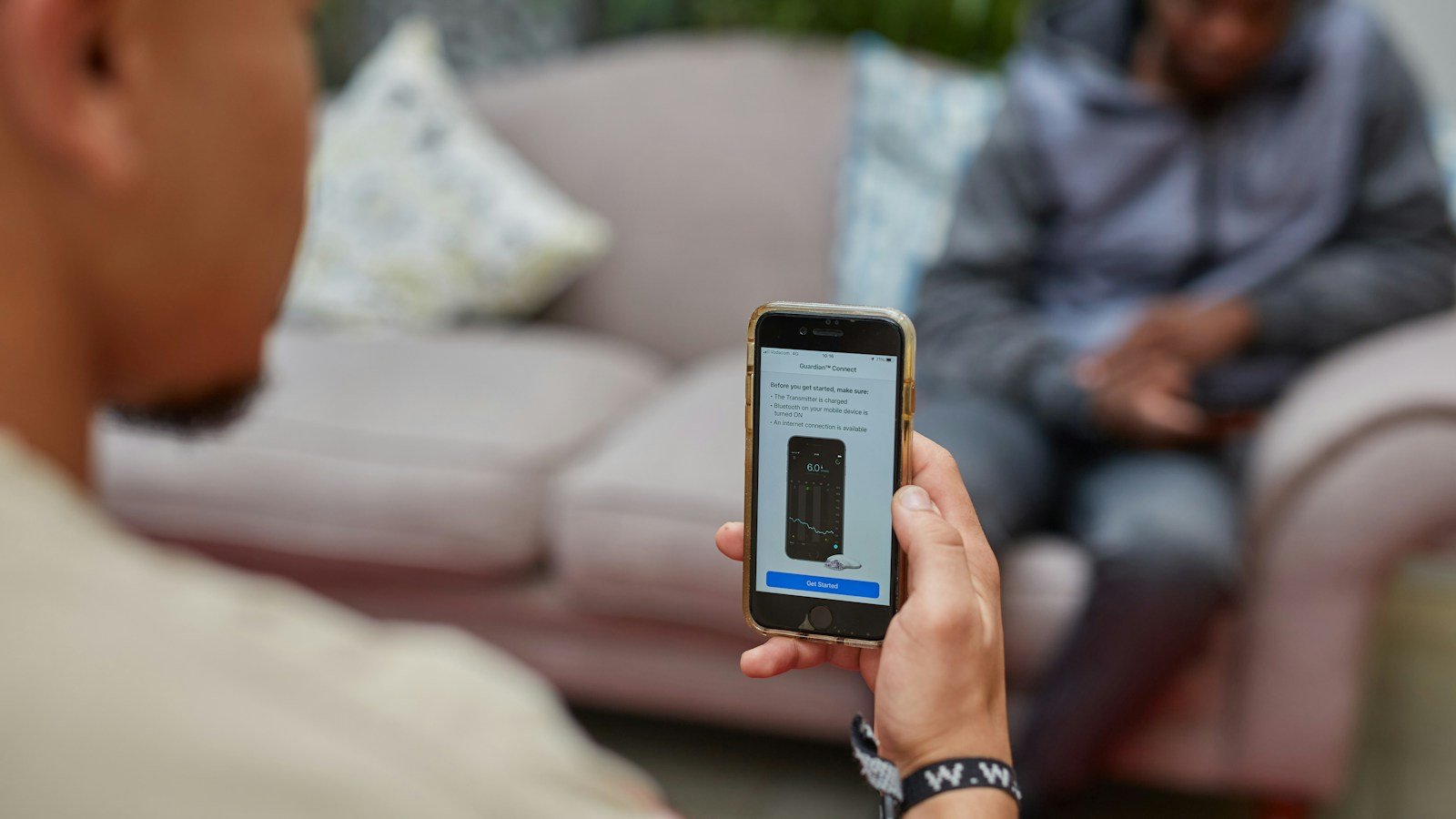 Foto ilustrativa de pessoa segurando celular com aplicativo de monitoramento contínuo de glicose; não mostra os modelos da EASD 2026